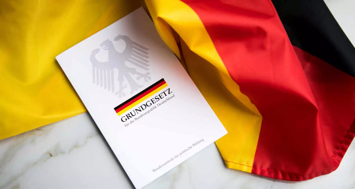 Grundgesetz-Buch der Bundesrepublik Deutschland auf Flagge. Foto: Adobe Stock | Christin Klose