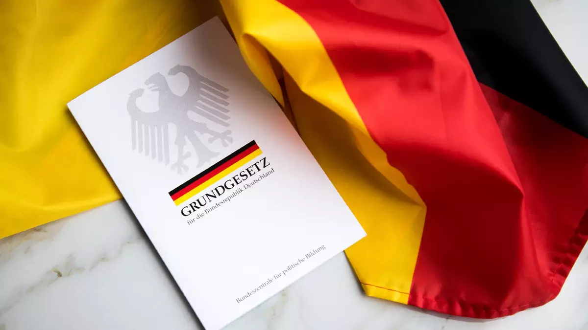 Grundgesetz-Buch der Bundesrepublik Deutschland auf Schwarz-Rot-Gold-Flagge. Foto: Adobe Stock | Christin Klose Grundgesetz-Buch der Bundesrepublik Deutschland auf Schwarz-Rot-Gold-Flagge. Foto: Adobe Stock | Christin Klose