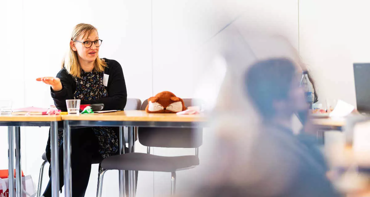Lehrerin am Tisch beim Spechen. Foto: Andreas Gregor